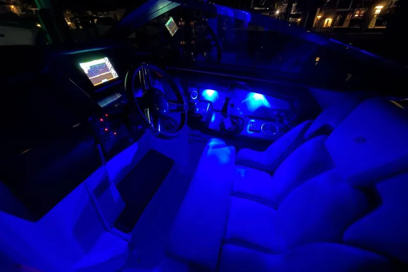 Slide: The Image of 2022 Four Winns H290 OB boat interior with blue ambient lighting and modern dashboard. - 21