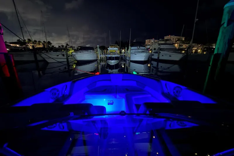 Slide: The Image of 2022 Four Winns H290 OB boat with blue interior lights docked at night. - 22