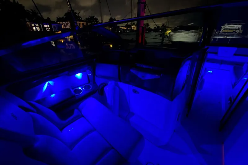 Slide: The Image of 2022 Four Winns H290 OB boat interior illuminated with blue LED lights at night. - 23