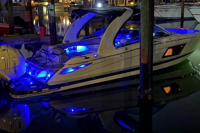 Slide: The Image of 2022 Four Winns H290 OB boat with blue LED lights docked at night. - 24