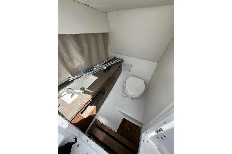 Slide: The Image of Interior of 2022 Four Winns H290 OB boat featuring compact bathroom with sink and toilet. - 4