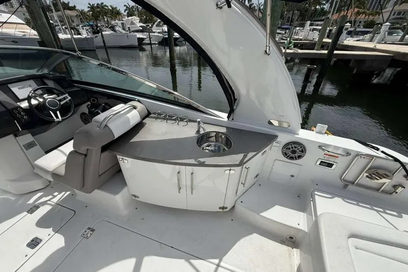 Slide: The Image of 2022 Four Winns H290 OB boat interior with helm, sink, and seating area. - 8