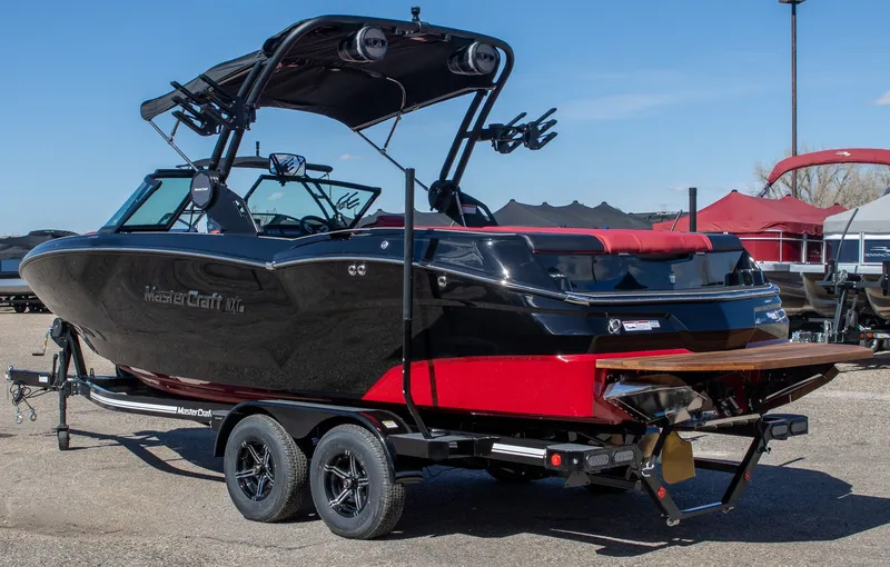Slide: The Image of 2024 MasterCraft NXT23 boat on trailer, black and red, side view. - 3