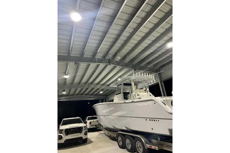 Slide: The Image of 2025 Freeman 35 boat on trailer in a well-lit garage with trucks nearby. - 3