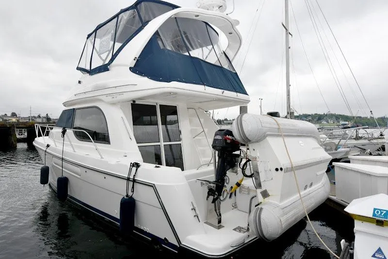 Slide: The Image of 2001 Bayliner 3788 Command Bridge Motoryacht docked, featuring blue canopy and inflatable dinghy. - 2