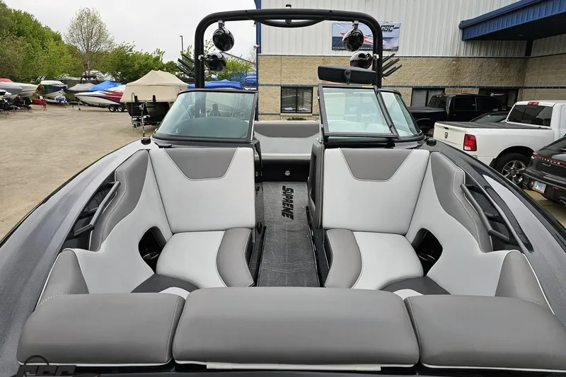 Slide: The Image of 2018 Supreme S226 boat interior with gray and white seating, parked outdoors. - 19