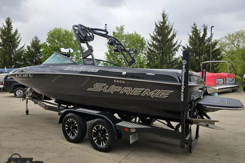 Slide: The Image of 2018 Supreme S226 boat on trailer, parked outdoors with trees in background. - 31