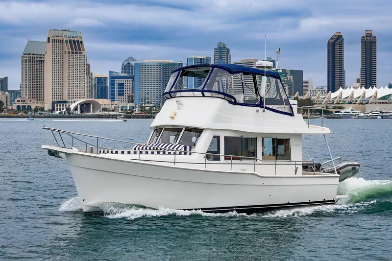 The Image of 2011 Mainship 395 Trawler cruising in urban waterfront setting with city skyline backdrop. - 0