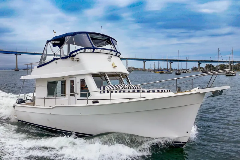 Slide: The Image of 2011 Mainship 395 Trawler cruising on water with bridge and sailboats in background. - 10