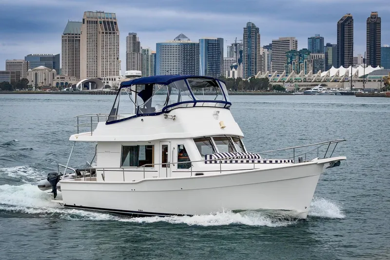 Slide: The Image of 2011 Mainship 395 Trawler cruising near a city skyline on a cloudy day. - 11