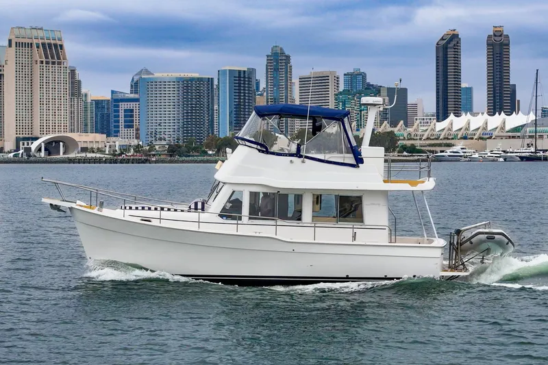 Slide: The Image of 2011 Mainship 395 Trawler cruising near city skyline, showcasing modern design and urban backdrop. - 12