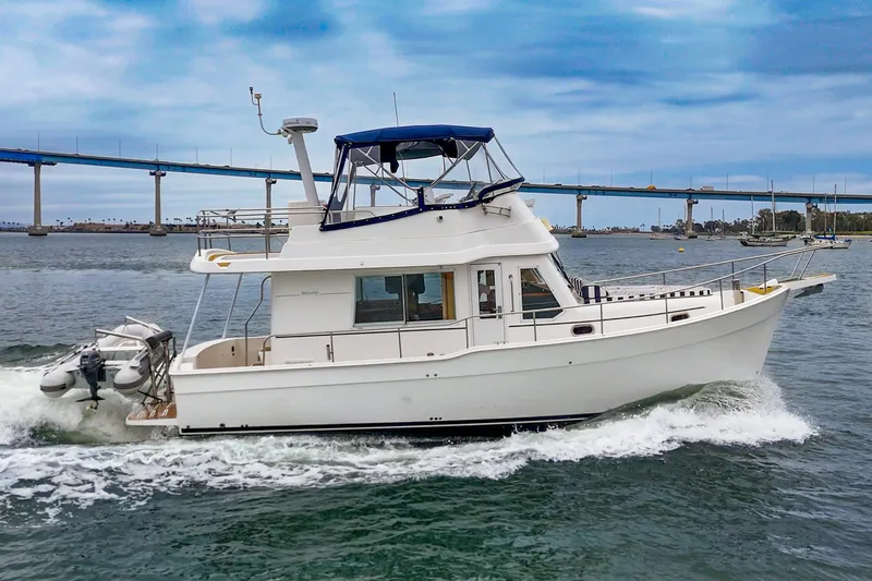 Slide: The Image of 2011 Mainship 395 Trawler cruising on water near a bridge under a blue sky. - 13