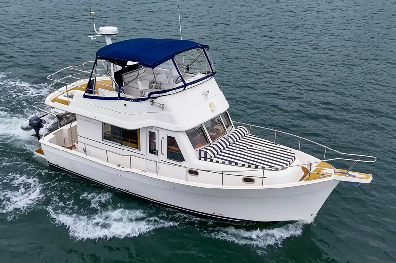 Slide: The Image of 2011 Mainship 395 Trawler cruising on open water with blue canopy and striped deck cushions. - 14