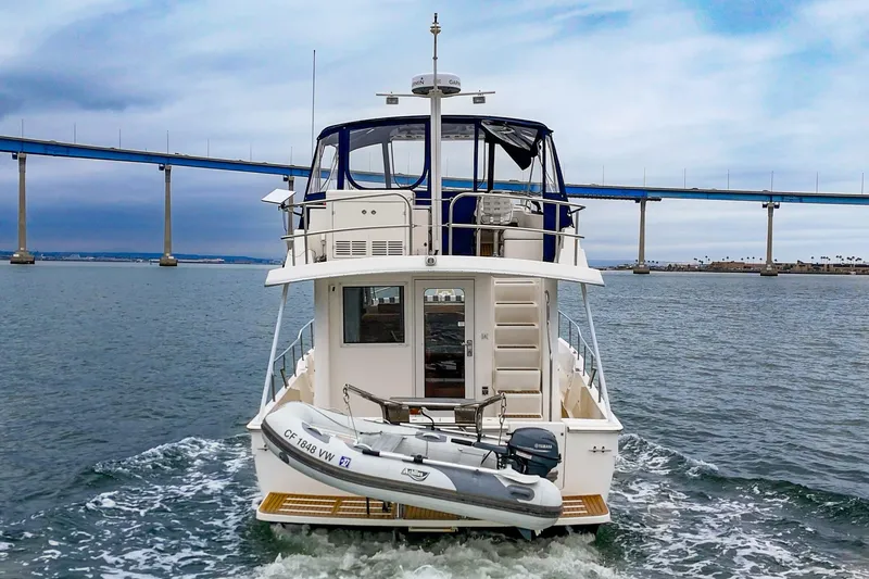Slide: The Image of 2011 Mainship 395 Trawler cruising under a bridge on a cloudy day. - 18