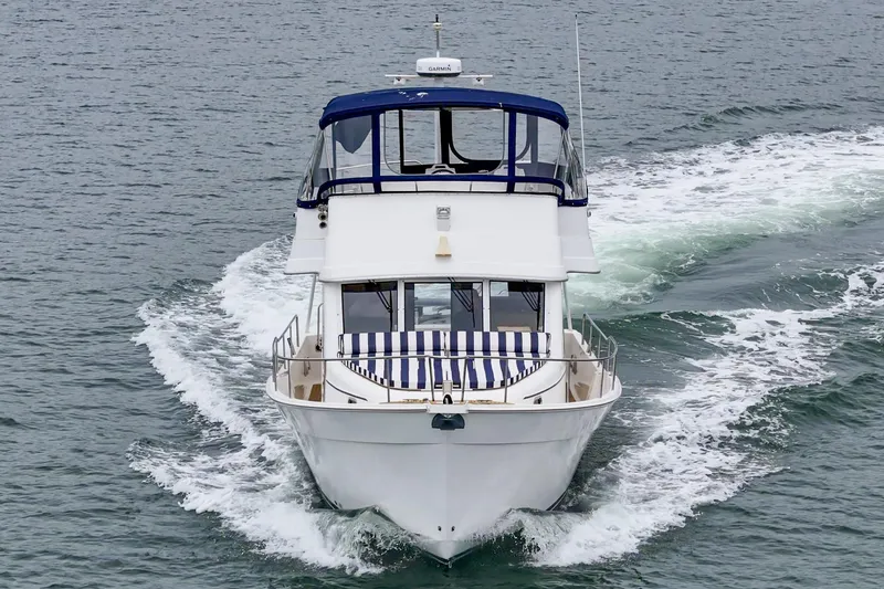 Slide: The Image of 2011 Mainship 395 Trawler cruising on open water, showcasing sleek design and blue canopy. - 19