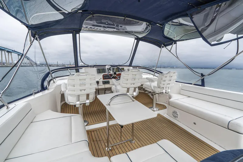Slide: The Image of 2011 Mainship 395 Trawler interior with seating, table, and helm, overlooking water and bridge. - 2