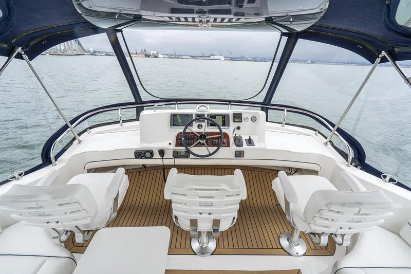 Slide: The Image of Cockpit view of 2011 Mainship 395 Trawler with three white chairs and navigational controls. - 23