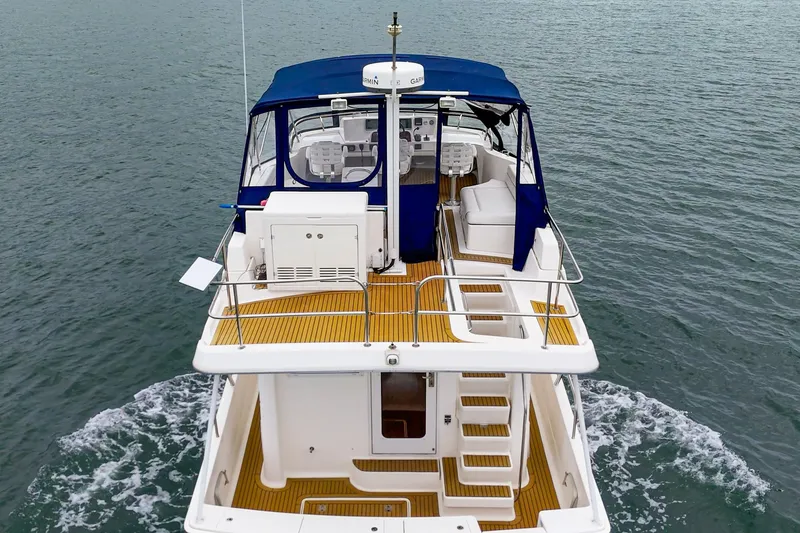Slide: The Image of 2011 Mainship 395 Trawler cruising on water, featuring blue canopy and spacious deck. - 28