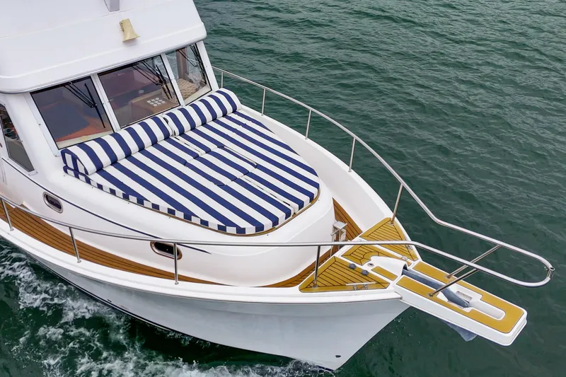 Slide: The Image of 2011 Mainship 395 Trawler with striped sunbed, cruising on open water. - 3