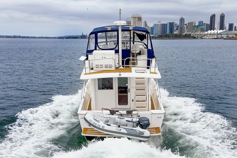 Slide: The Image of 2011 Mainship 395 Trawler cruising near city skyline on a cloudy day. - 30