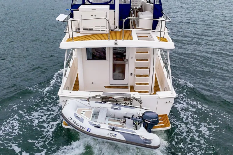 Slide: The Image of 2011 Mainship 395 Trawler cruising with attached dinghy on open water. - 31