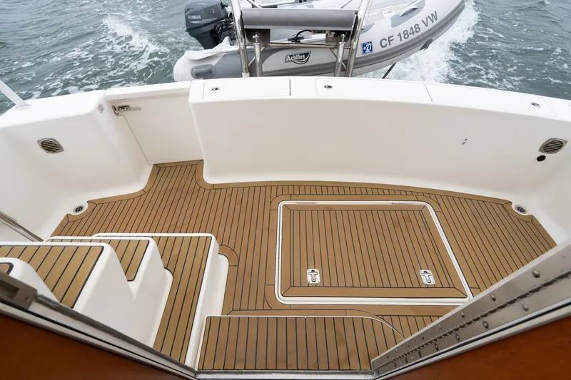 Slide: The Image of Mainship 395 Trawler 2011 deck with teak flooring and attached dinghy in water. - 33