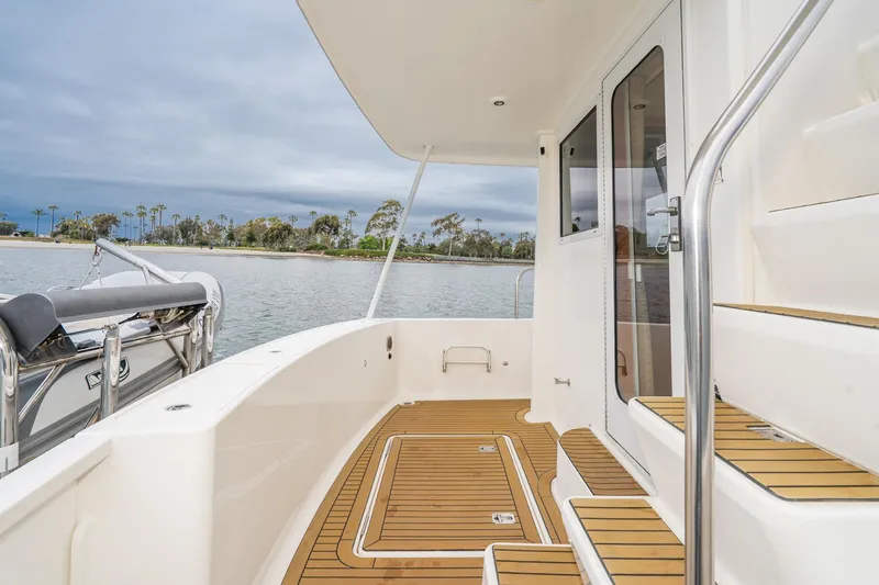 Slide: The Image of 2011 Mainship 395 Trawler deck with teak flooring, overlooking serene waters and lush shoreline. - 34
