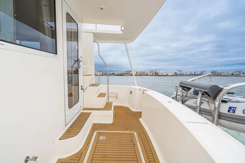 Slide: The Image of 2011 Mainship 395 Trawler deck with wooden flooring, overlooking calm waters. - 35