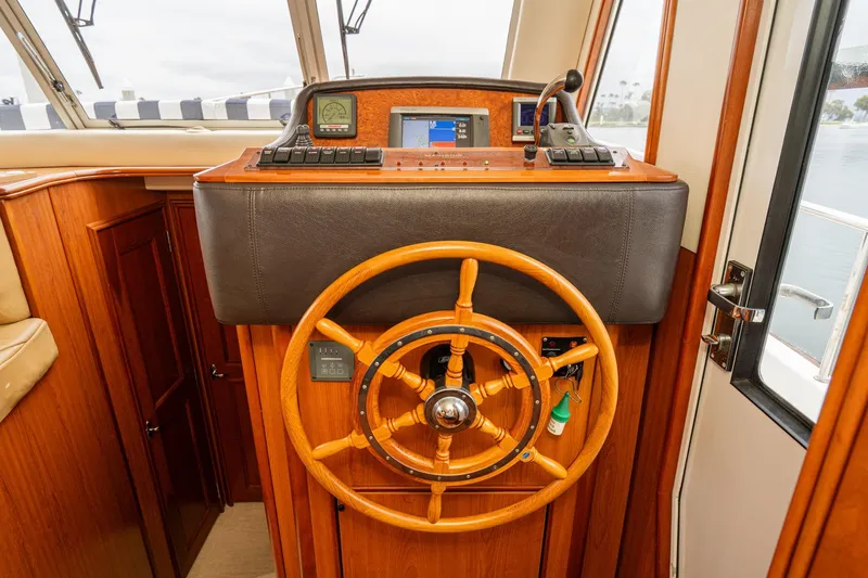 Slide: The Image of 2011 Mainship 395 Trawler helm with wooden steering wheel and navigation controls. - 48