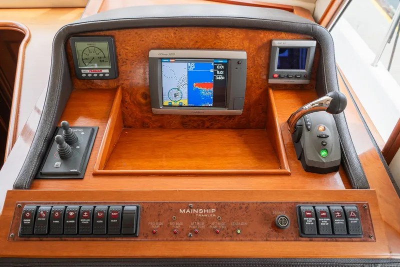 Slide: The Image of Control panel of a 2011 Mainship 395 Trawler with navigation and engine controls. - 49