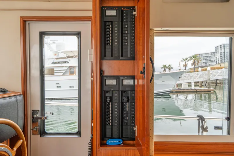 Slide: The Image of Interior view of 2011 Mainship 395 Trawler showing electrical panel and marina through windows. - 52