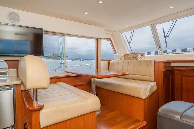 Slide: The Image of Interior of 2011 Mainship 395 Trawler with beige seating, wooden table, and large windows. - 53