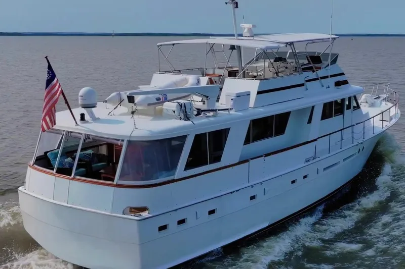 Slide: The Image of 1980 Hatteras 70 Motor Yacht cruising on open water with American flag. - 4