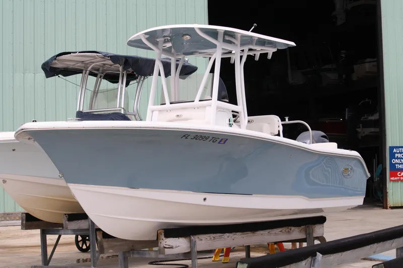 The Image of 2022 Sea Hunt Ultra 219 boat in storage, featuring a sleek blue and white design. - 0