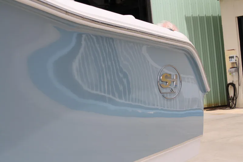Slide: The Image of 2022 Sea Hunt Ultra 219 boat side view with logo, near a green building. - 4