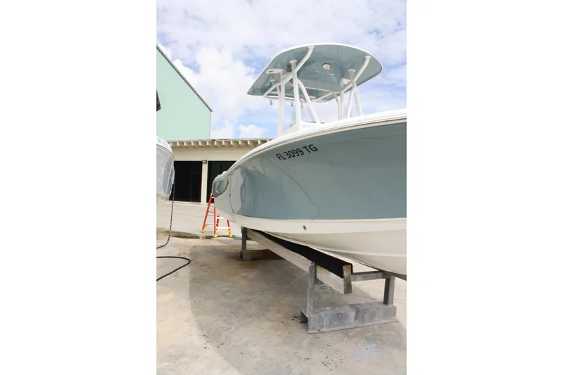 Slide: The Image of 2022 Sea Hunt Ultra 219 boat on a stand, light blue hull, outdoor setting. - 9
