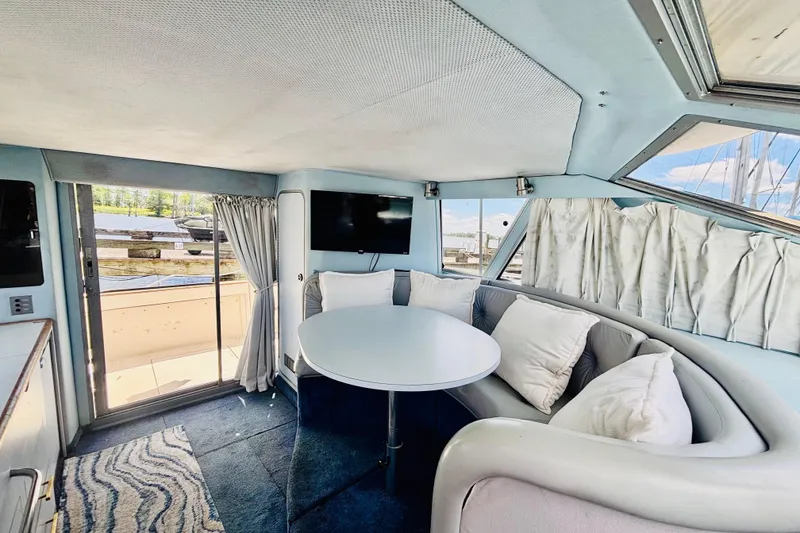 Slide: The Image of Interior of 1988 Sea Ray 305 Sedan Bridge with cozy seating and round table. - 10