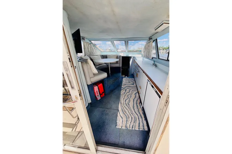 Slide: The Image of Interior of a 1988 Sea Ray 305 Sedan Bridge, featuring seating and a compact kitchen area. - 8