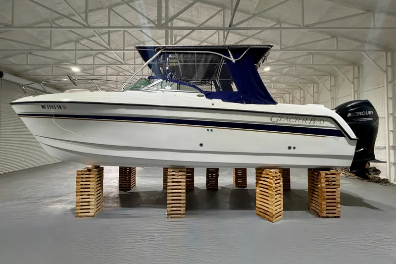 The Image of 2006 Glacier Bay 2640SX Renegade boat elevated on wooden blocks in a spacious indoor facility. - 1