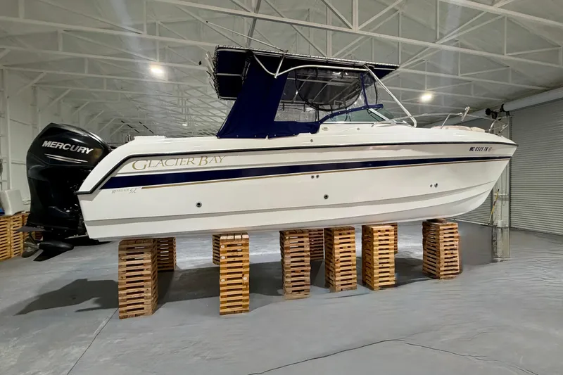 Slide: The Image of 2006 Glacier Bay 2640SX Renegade boat on wooden blocks in a spacious indoor facility. - 2