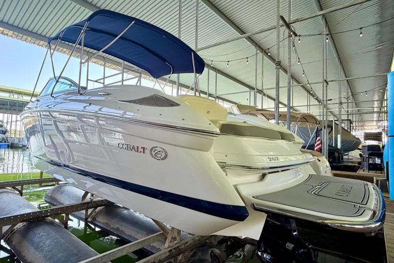 Slide: The Image of 2013 Cobalt 262 boat with blue canopy docked in a covered marina. - 18