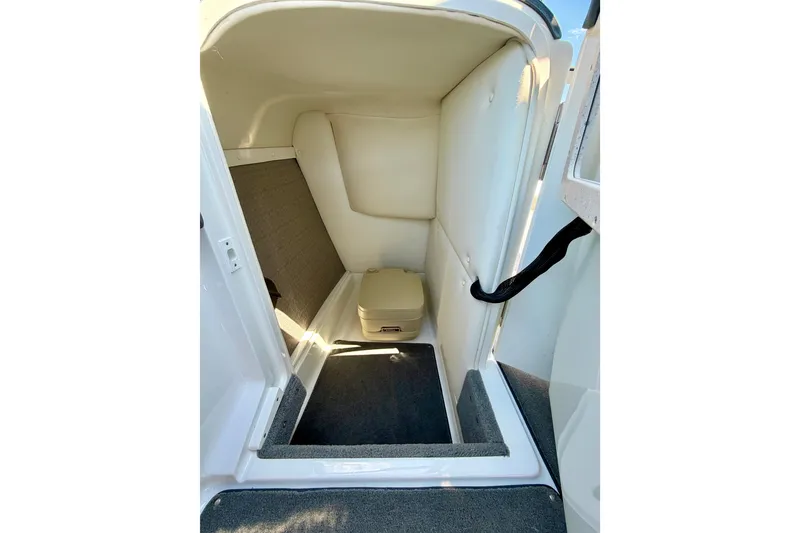 Slide: The Image of 2013 Cobalt 262 boat interior with compact restroom and beige seating. - 35