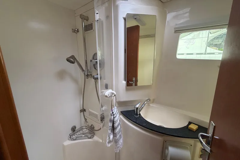 Slide: The Image of Compact yacht bathroom with shower, sink, mirror, and window in a 2007 Leopard 46. - 20