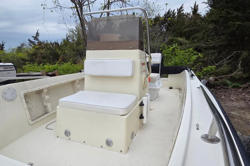 Slide: The Image of 1995 Sportsman Island Reef 19 Center Console boat with white seating and console, surrounded by greenery. - 6