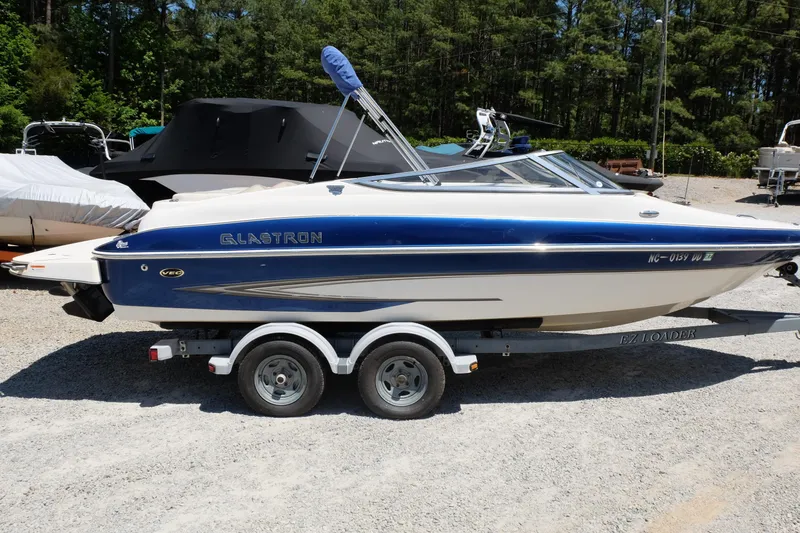 The Image of 2006 Glastron GXL 205 boat on trailer, parked outdoors in a sunny setting. - 0