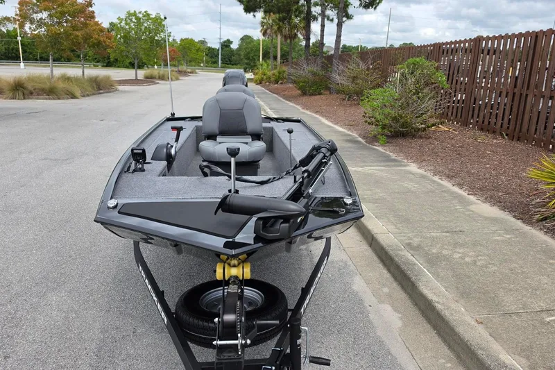 Slide: The Image of 2026 Tracker Panfish 17 boat on trailer, parked on a paved road near greenery. - 10