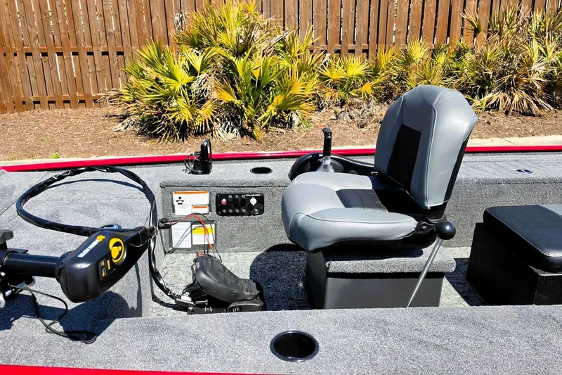 Slide: The Image of 2026 Tracker Panfish 17 boat interior with seating and control panel, surrounded by greenery. - 11