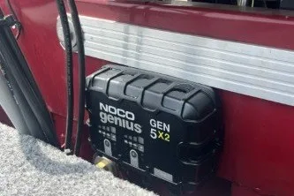 Slide: The Image of NOCO Genius GEN 5X2 charger on 2026 Tracker Panfish 17 boat, red exterior. - 7