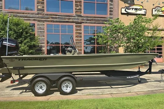 The Image of 2026 Tracker Grizzly 2072 CC boat on trailer, parked outside a building with large windows. - 0