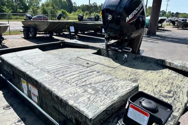 Slide: The Image of 2026 Tracker Grizzly 1860 CC boat with Mercury engine, parked outdoors. - 17
